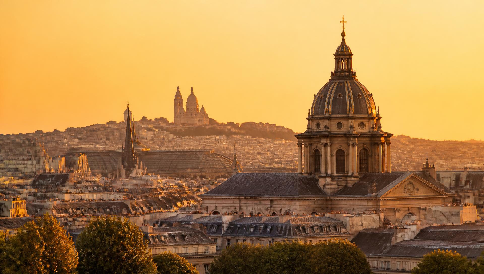 Golden-hour view over a classic city skyline with historic rooftops and a cathedral dome